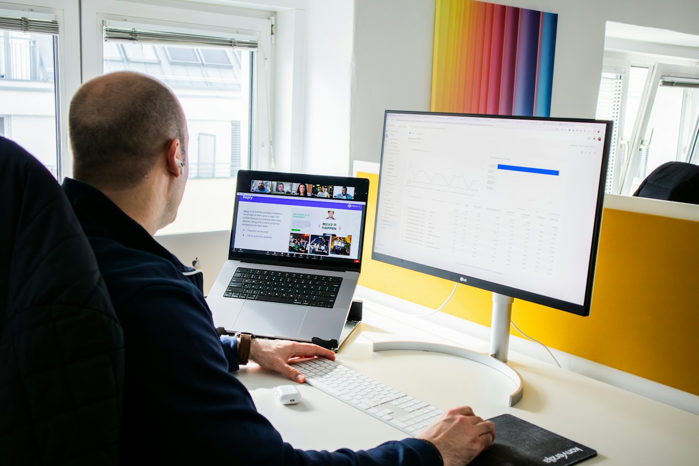 Mann arbeitet am Laptop und Monitor in einem modernen Büro.